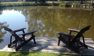 adirondac chairs sitting on a deck next to a pond